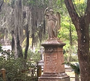 Wise Guys Historical Tours. A statue of an angel on a pedestal in what appears to be a cemetery