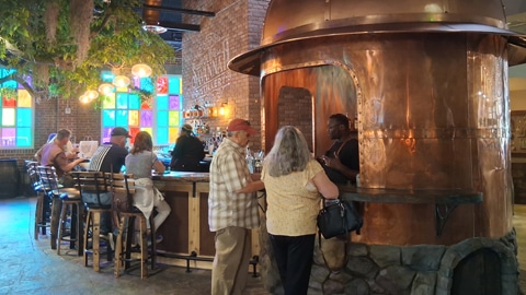 Old Savannah Distillery. a bar with a copper vat and stained glass windows