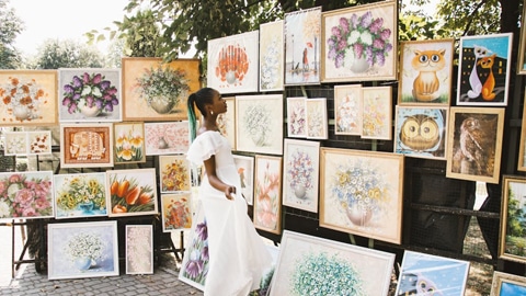 Support the Local Creative Community at Savannah's Local Artist Market. a woman looking at art
