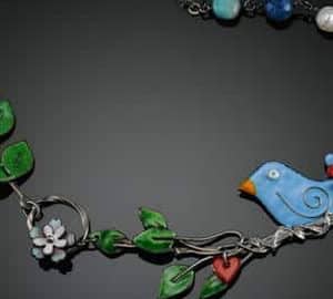 Signature Gallery. A necklace with a blue bird and leaves